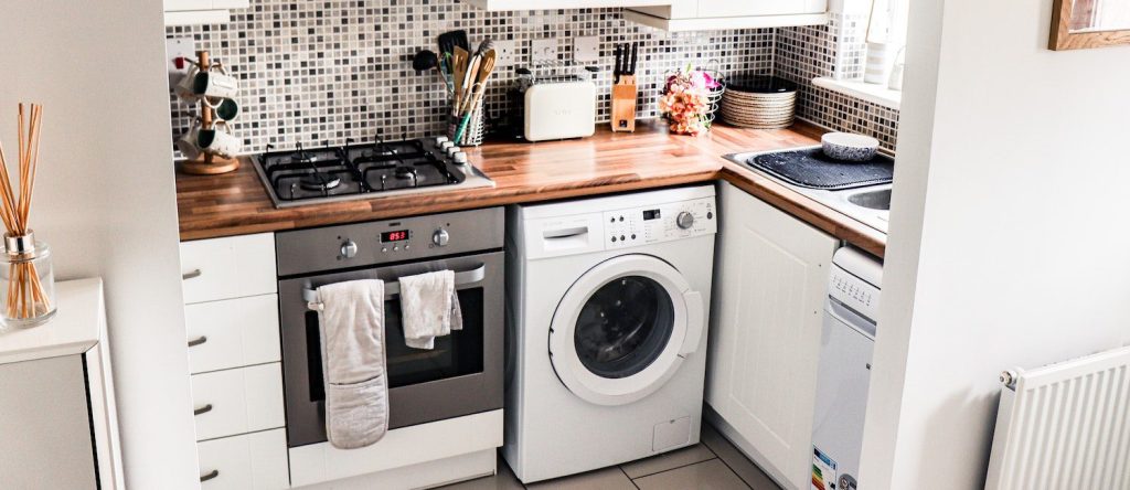 Small modern apartment kitchen with compact appliances on a white marble countertop