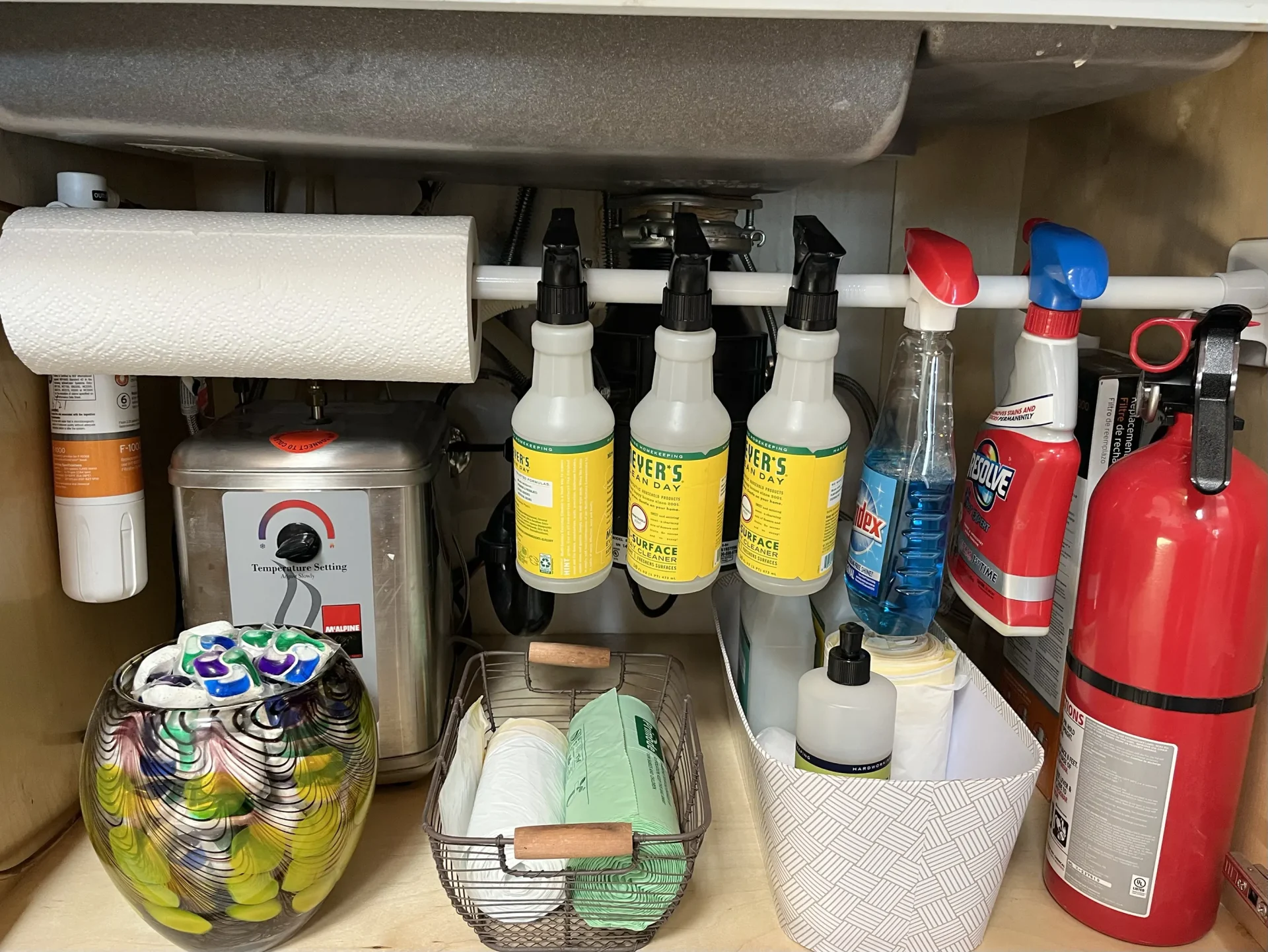 Tension rod under the sink organizing spray bottles for small kitchen storage