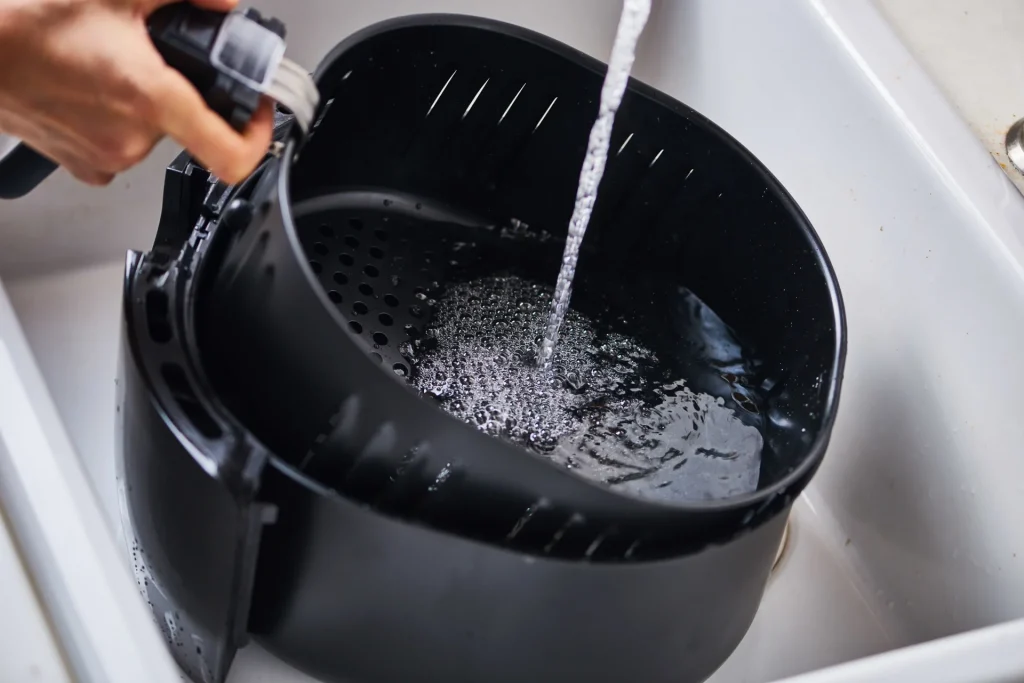 Soaking air fryer tray in water for cleaning