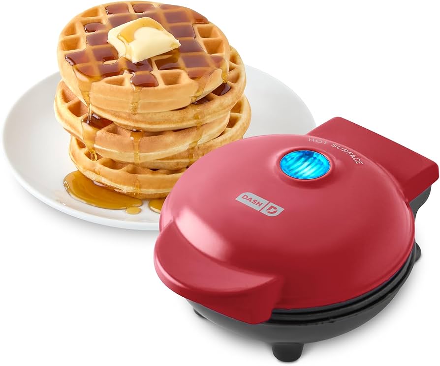 Dash Mini Waffle Maker cooking golden waffles on a kitchen counter with syrup and fruit nearby