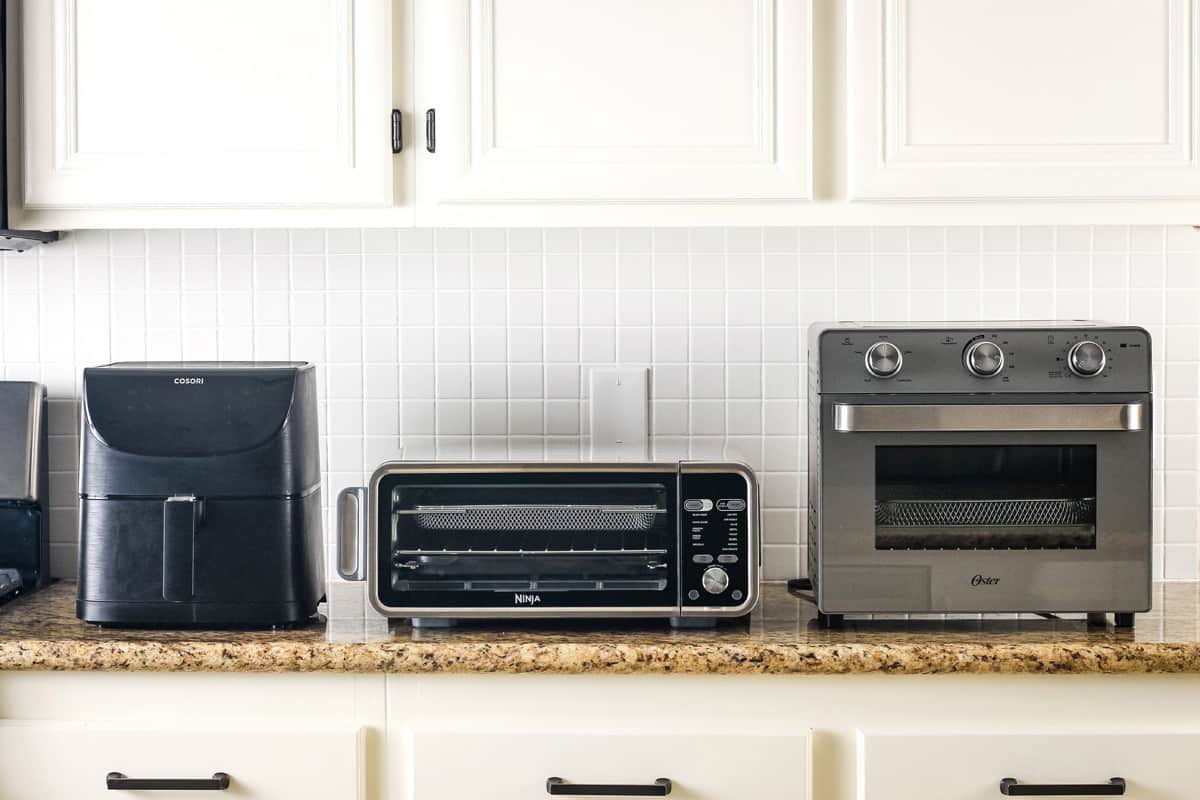 Air fryer and convection oven side by side on a kitchen countertop in a modern apartment