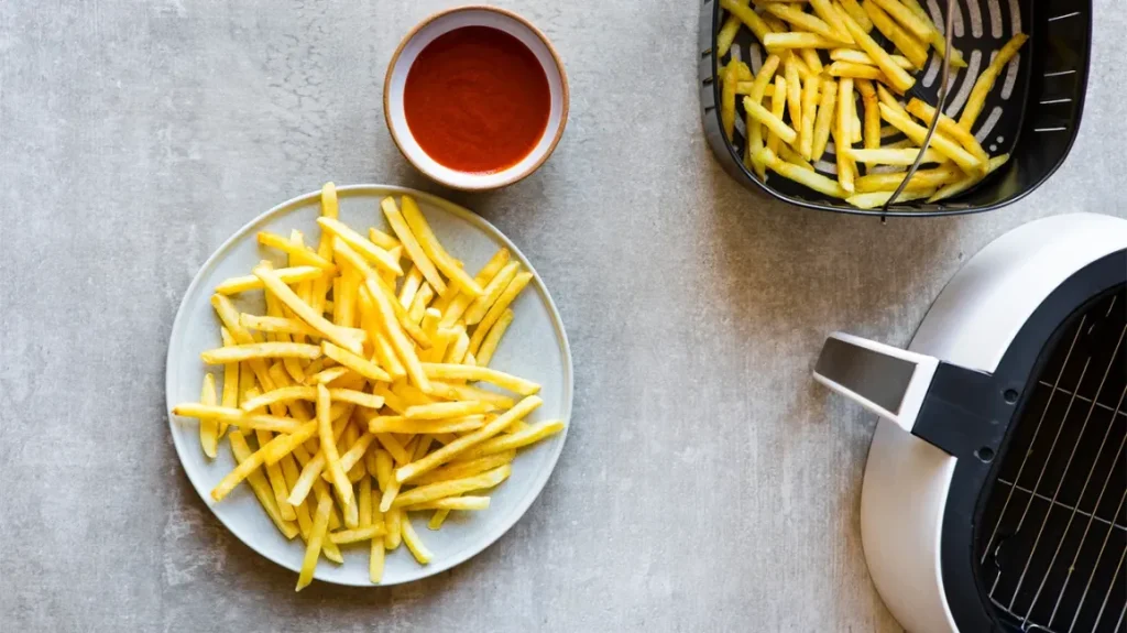 french fries on a plate beside an opened air fry basket
