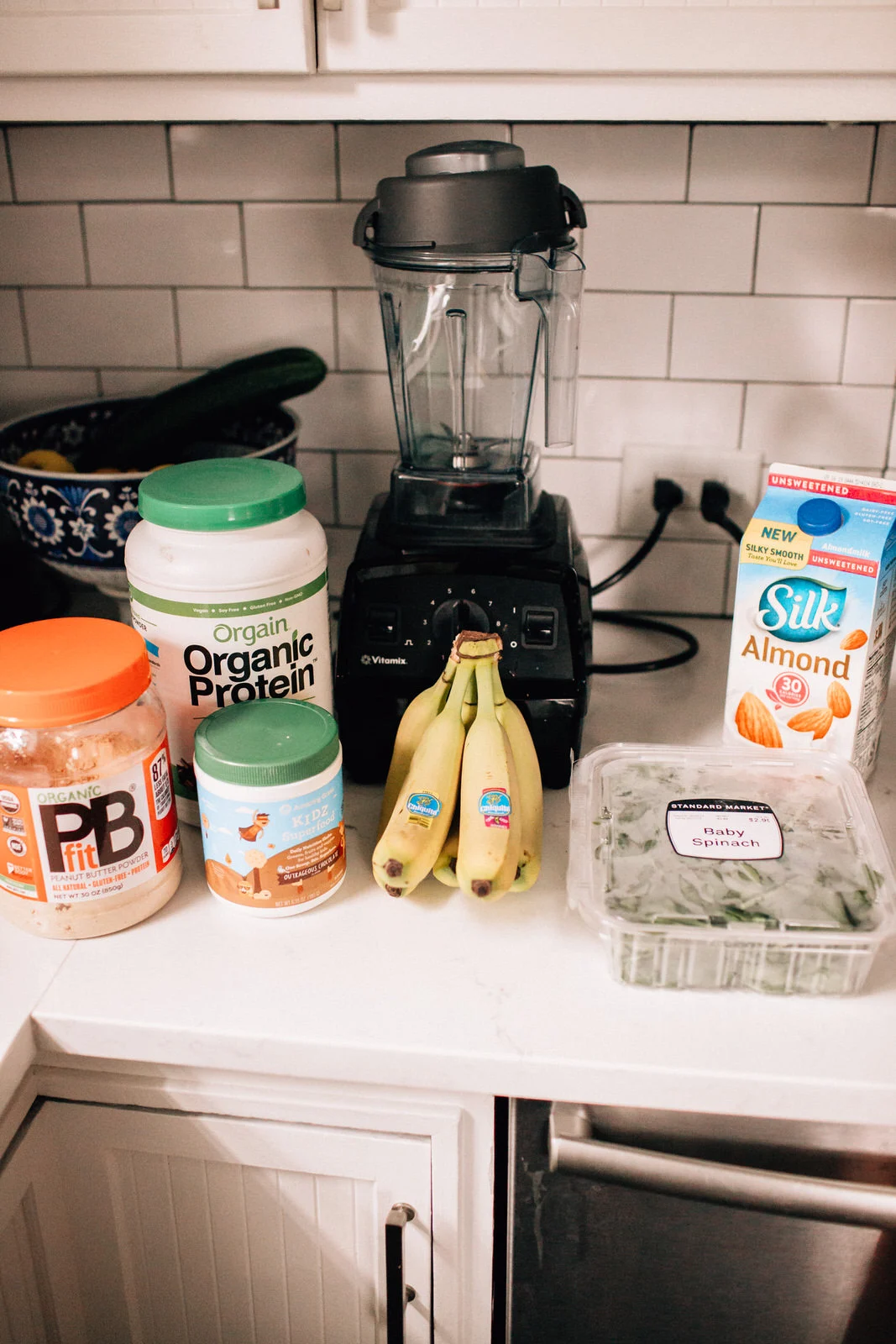 Family kitchen blender on countertop surrounded by fresh fruits and smoothie ingredients