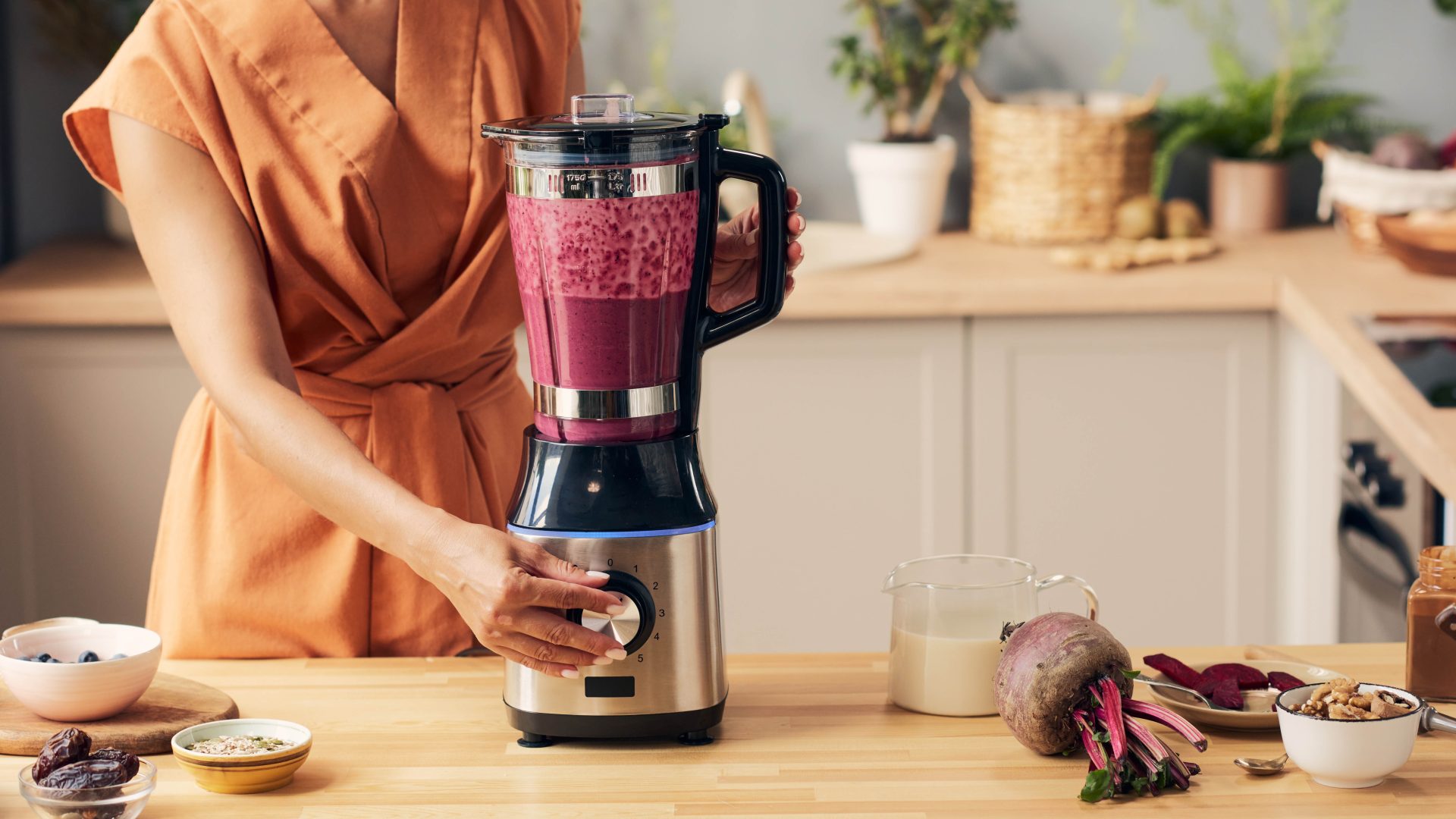 Person blending a smoothie in a stainless steel blender on a kitchen counter during routine maintenance