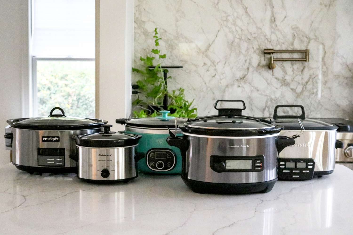 Collection of modern slow cookers arranged on a kitchen counter