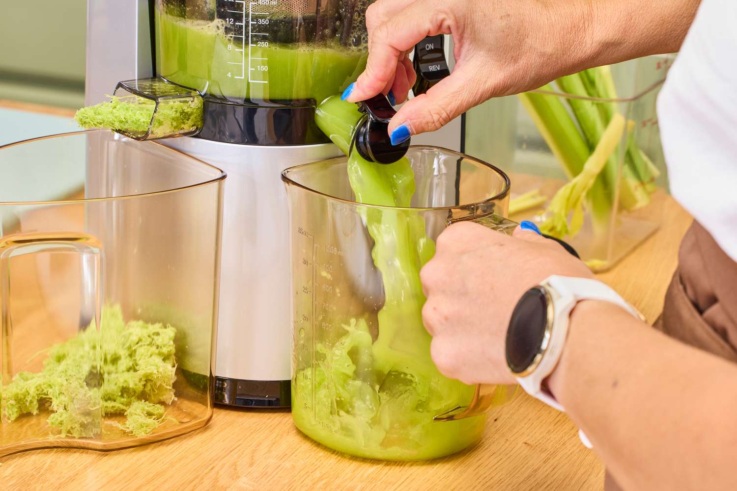Vertical slow-masticating juicer extracting juice from fruits on a kitchen counter