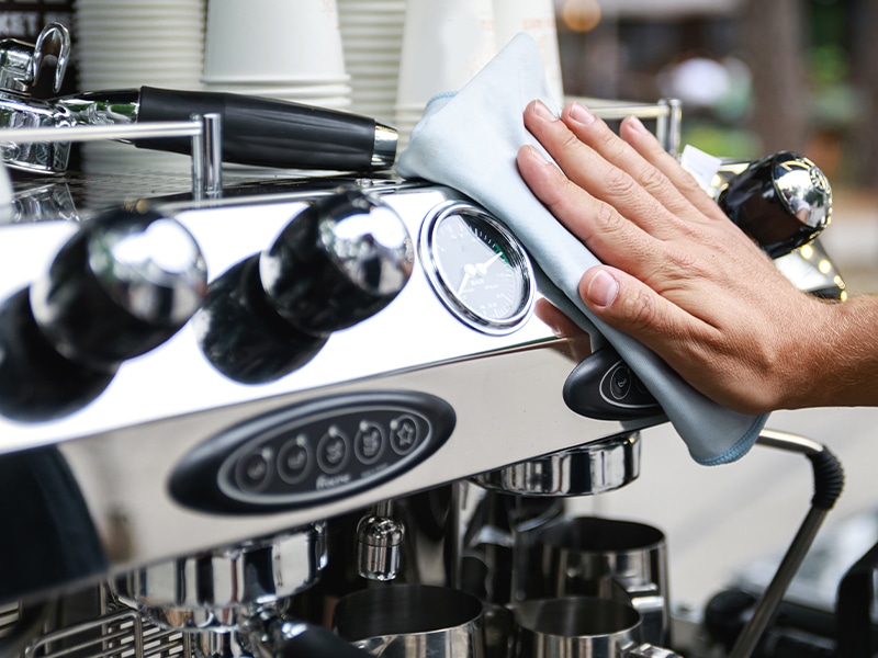 Wiping the exterior of a coffee machine during routine maintenance
