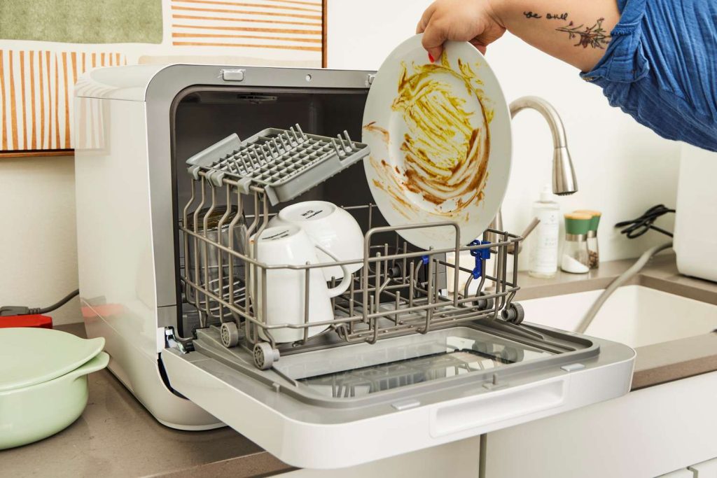 Compact countertop dishwasher washing dishes in a small apartment kitchen