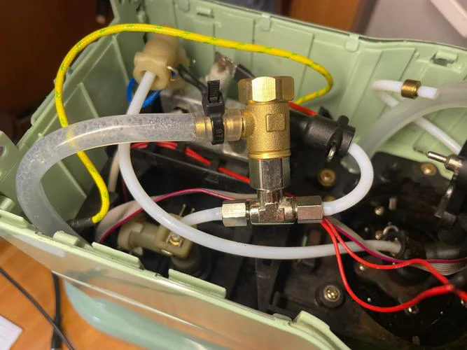 Internal tubing and valves inside a coffee maker showing the water pathway toward the heating element