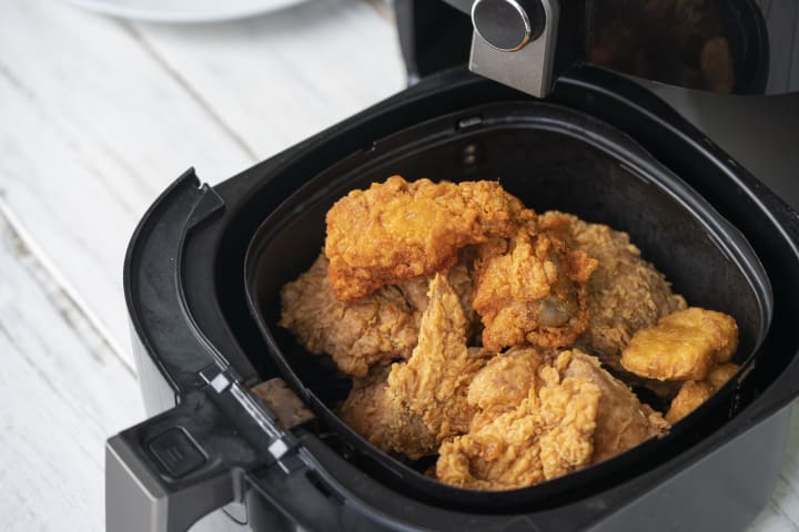 Air fryer basket filled close to capacity with overlapping fried chicken pieces