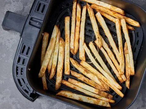 Air fryer basket with fries showing uneven browning, some darker and some lighter