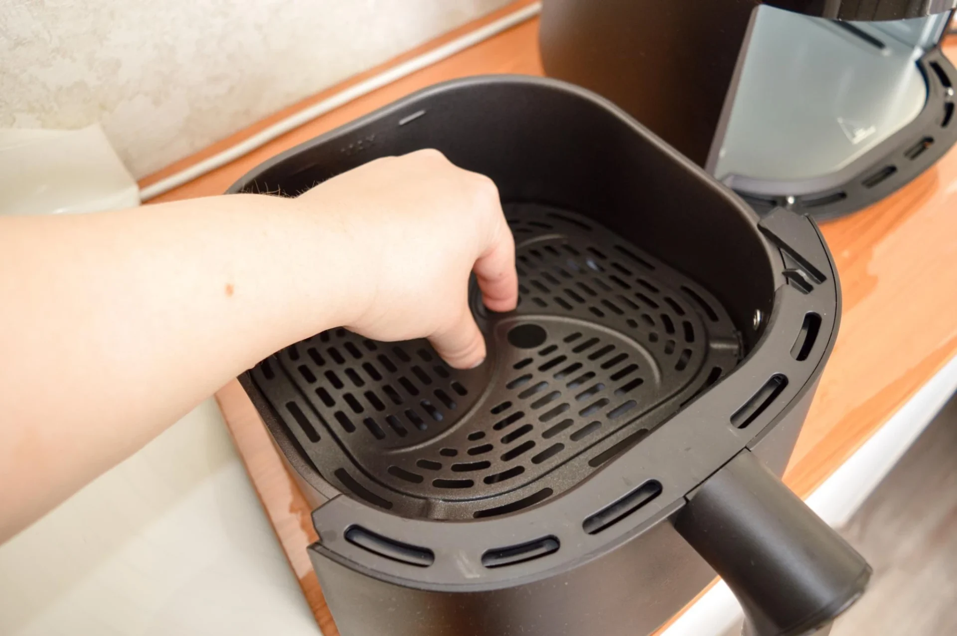 Checking the inside of an air fryer basket that feels cool despite the fan running