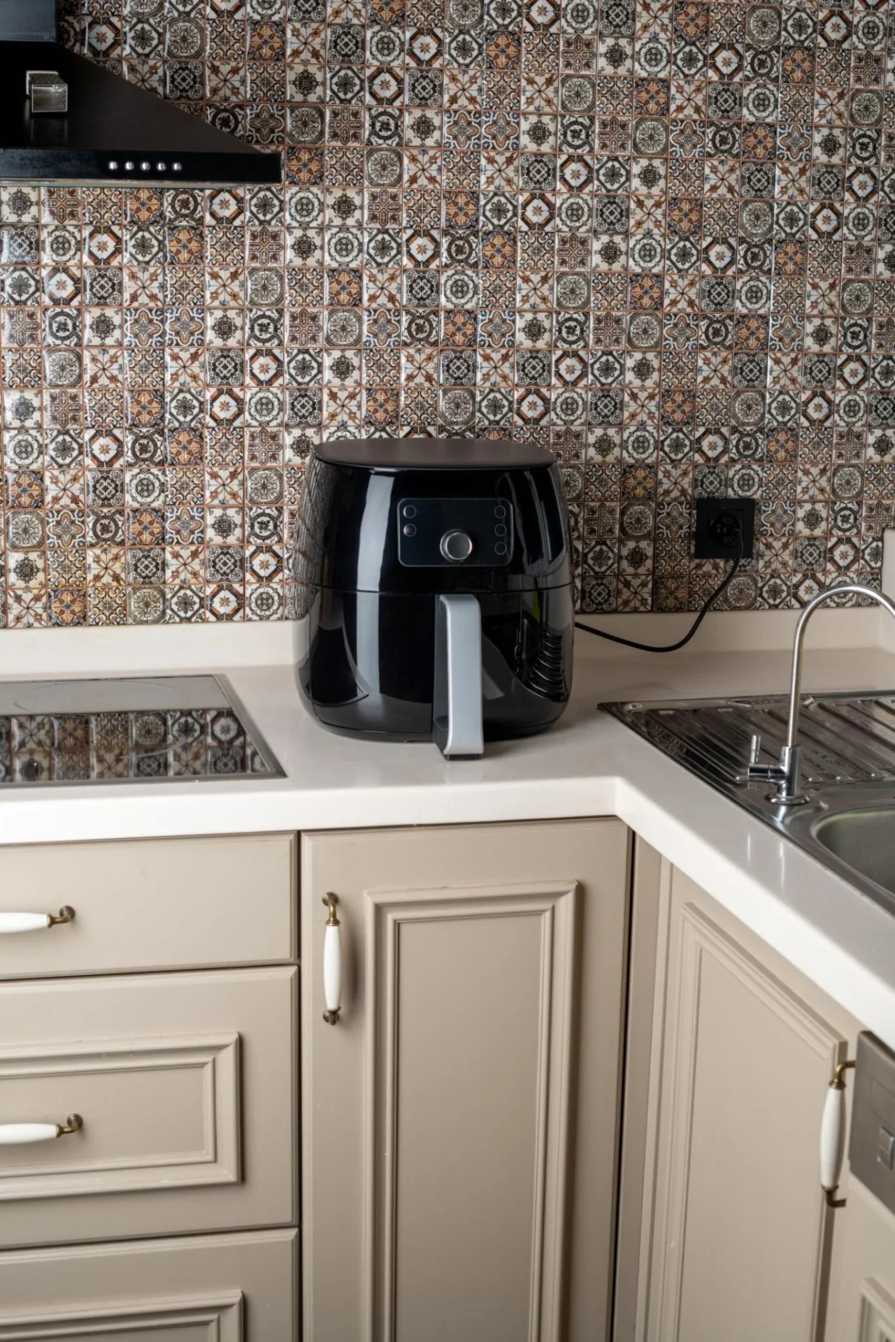 Air fryer placed close to a kitchen backsplash with limited clearance behind it