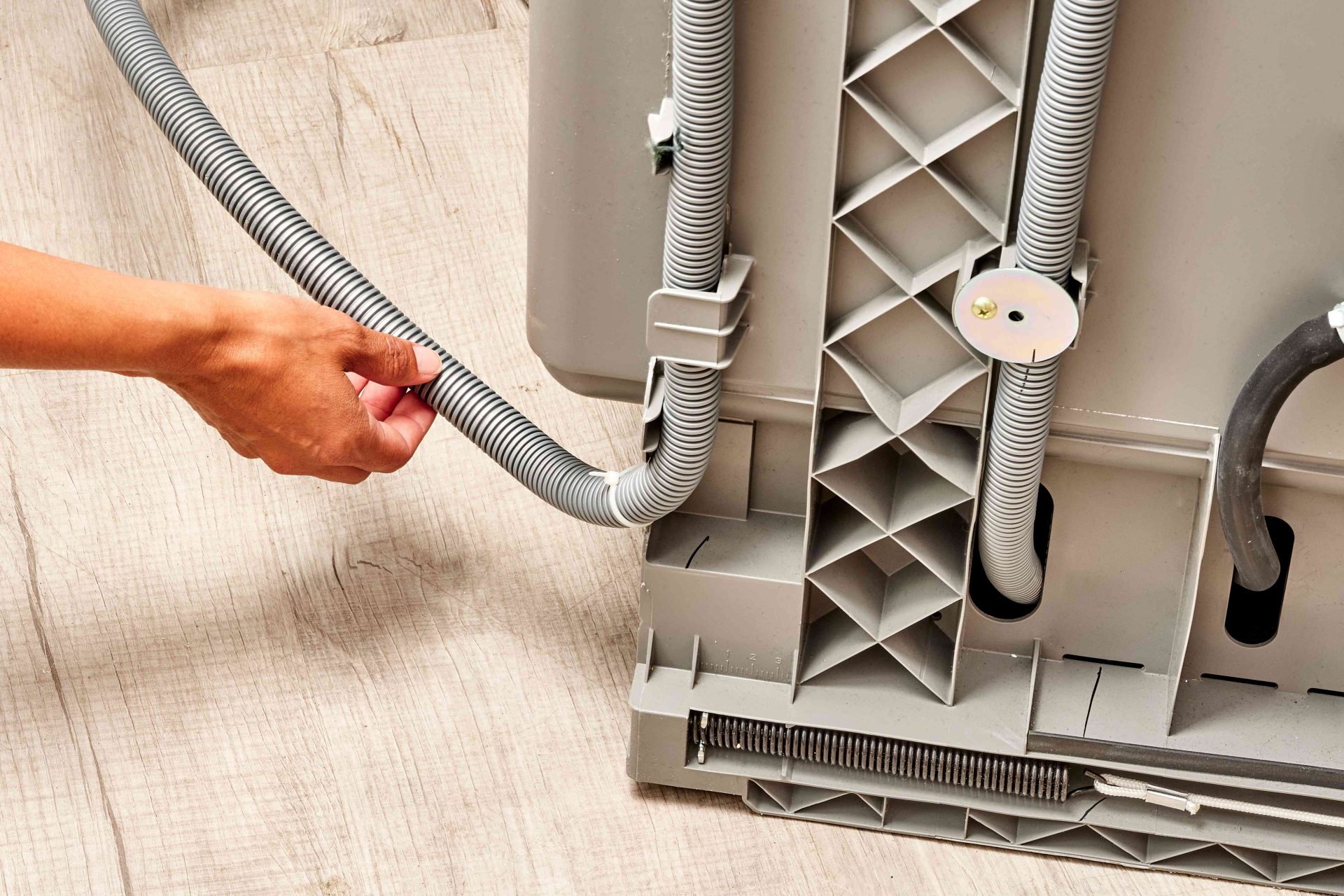 Hand adjusting a countertop dishwasher drain hose that is bent and restricting water flow